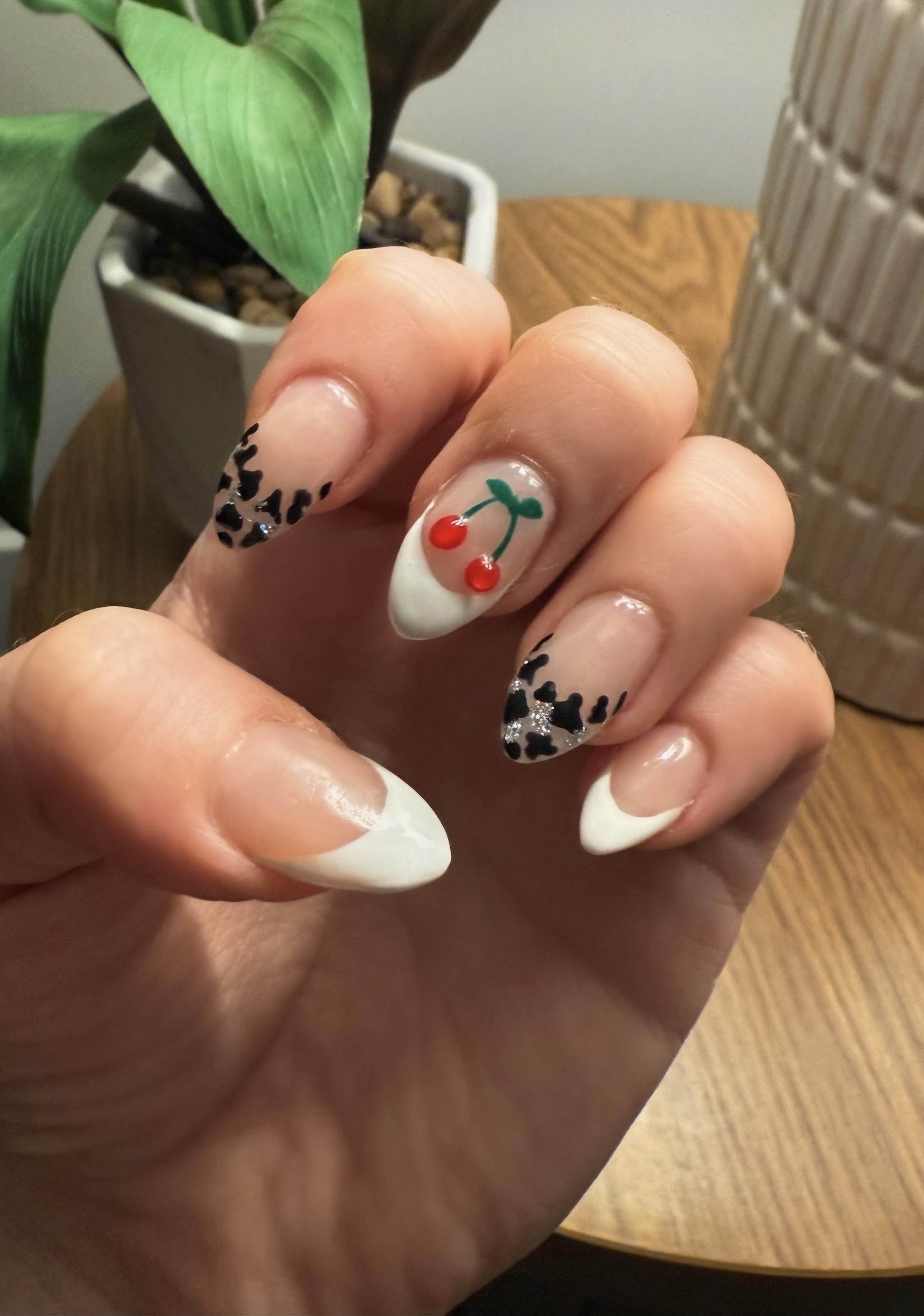 Almond nails with a French tip, cow print tips and a cherry accent